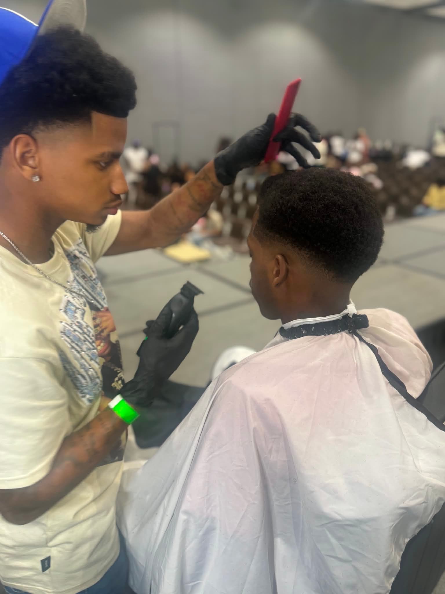 A barber shapes a client’s lineup with comb and trimmer on the B²E² 2026 expo floor.